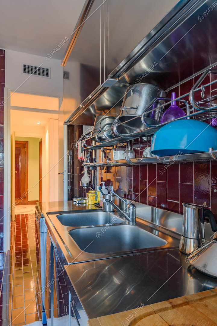 Tavolo da lavoro nella cucina con pareti e pavimento in piastrelle rosse lucide