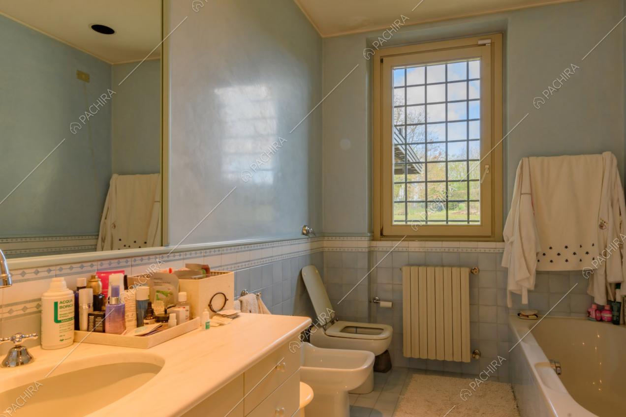 Grande bagno con vasca e piastrelle azzurre su pavimento e pareti