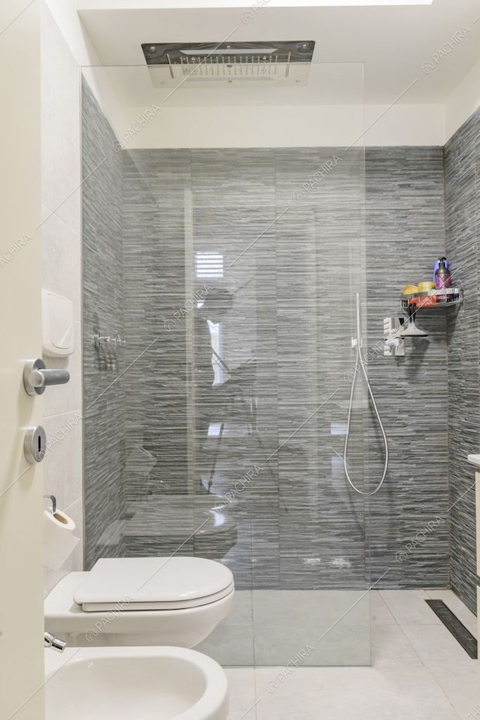 Bagno con ampio box doccia con parete in vetro
