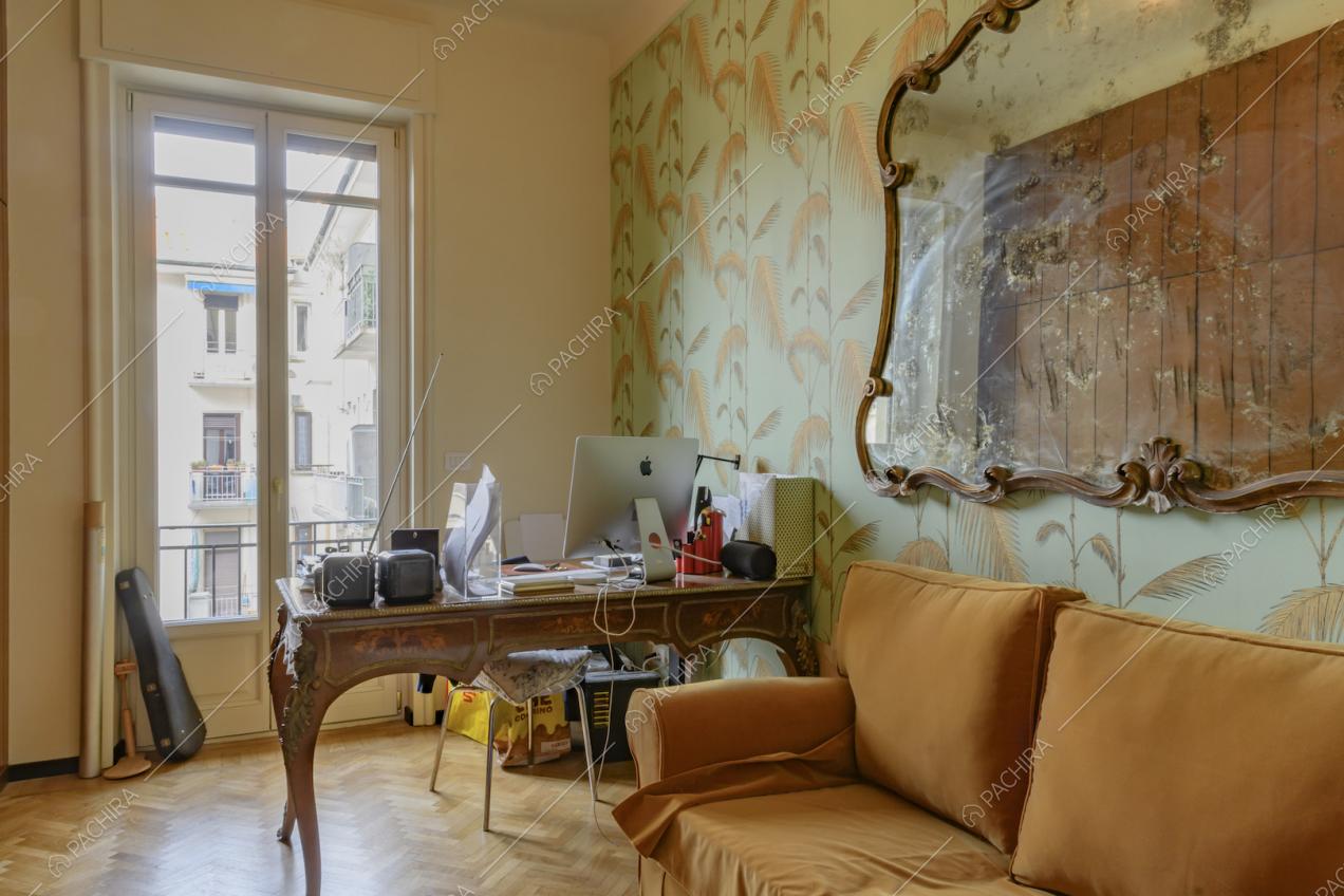 Studio con pavimento in parquet a spina di pesce, carta da parati e divano arancione