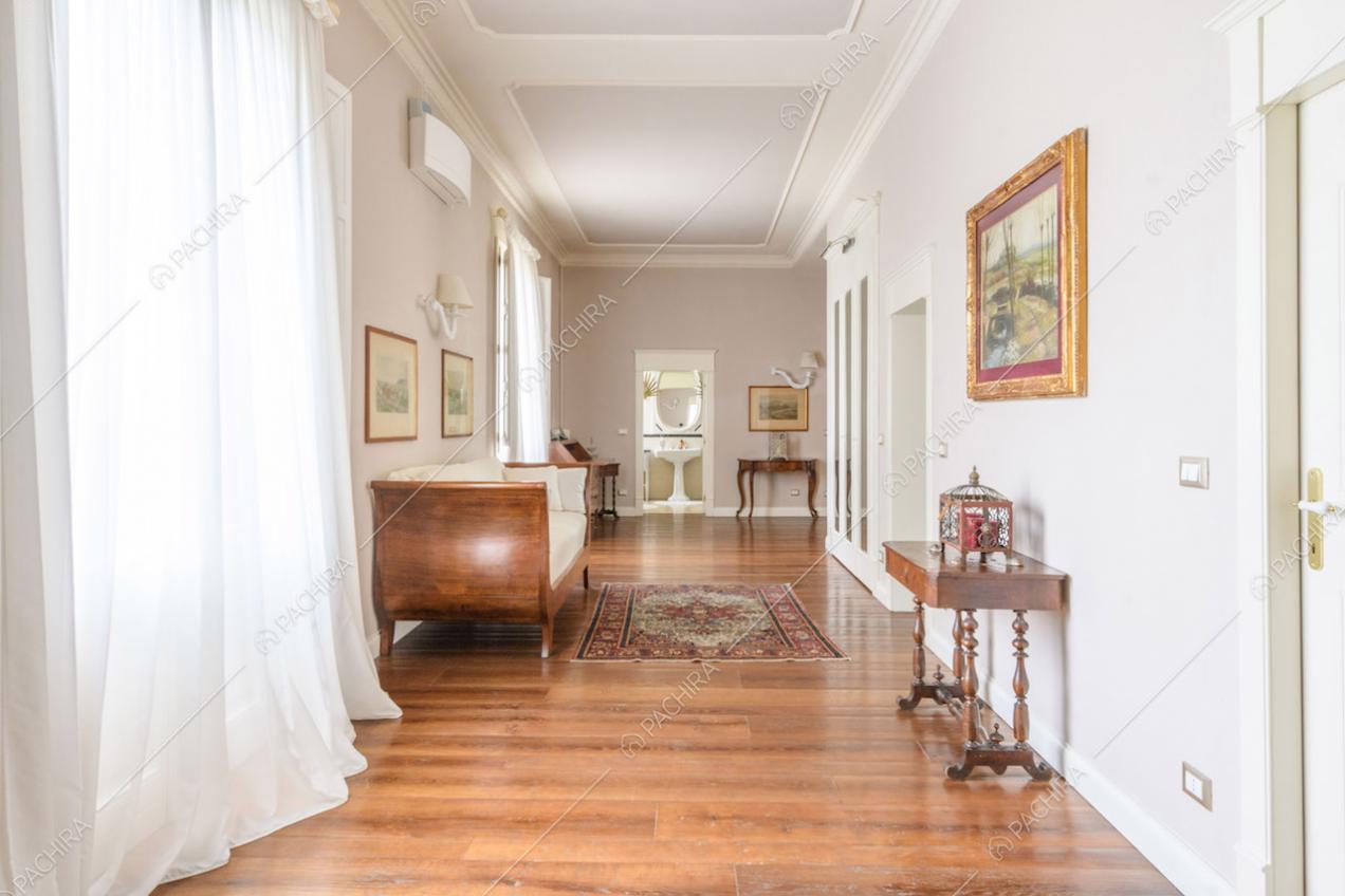 Boiserie sul soffitto nel corridoio con pavimento in parquet e vetrate