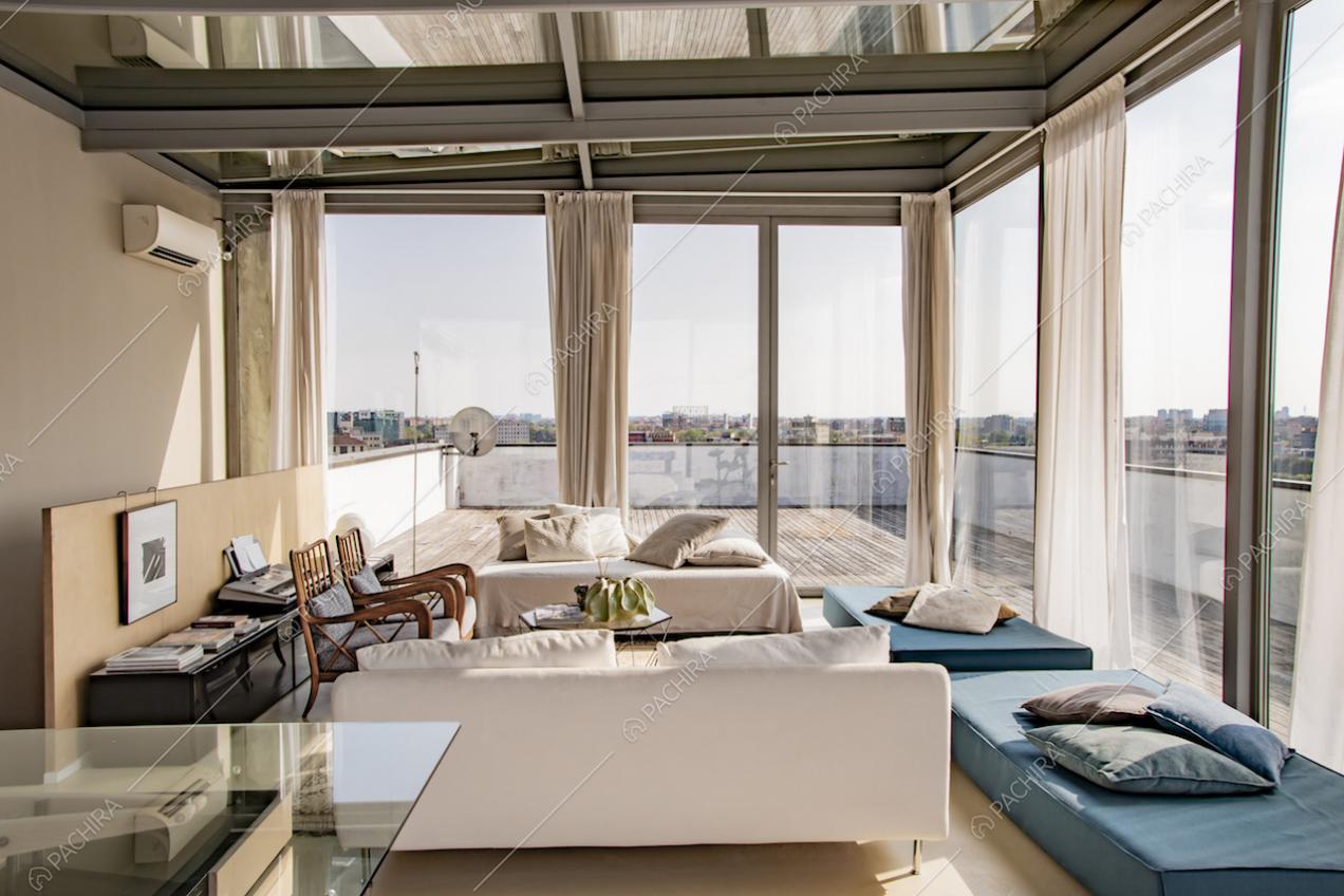 Zona living racchiusa da vetrate con vista sulla città