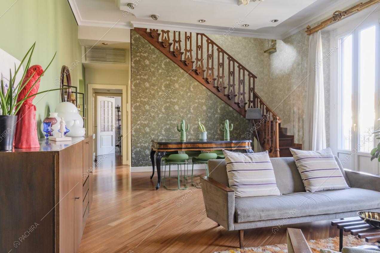 Divano grigio con cuscini e pavimento in parquet