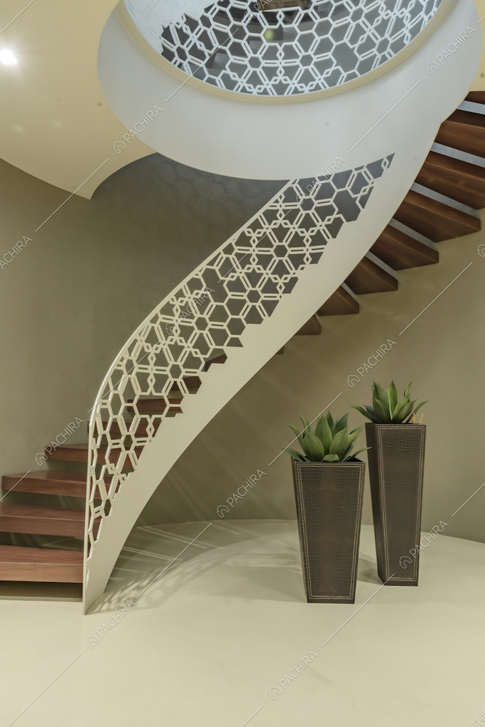 Scala a chiocciola con gradini il legno e balaustra bianca con fantasia geometrica