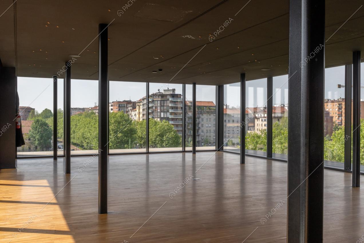 Dall'ampio salone dell'attico con colonne nere in metallo, ampie vetrate e pavimento in parquet, vista su Milano