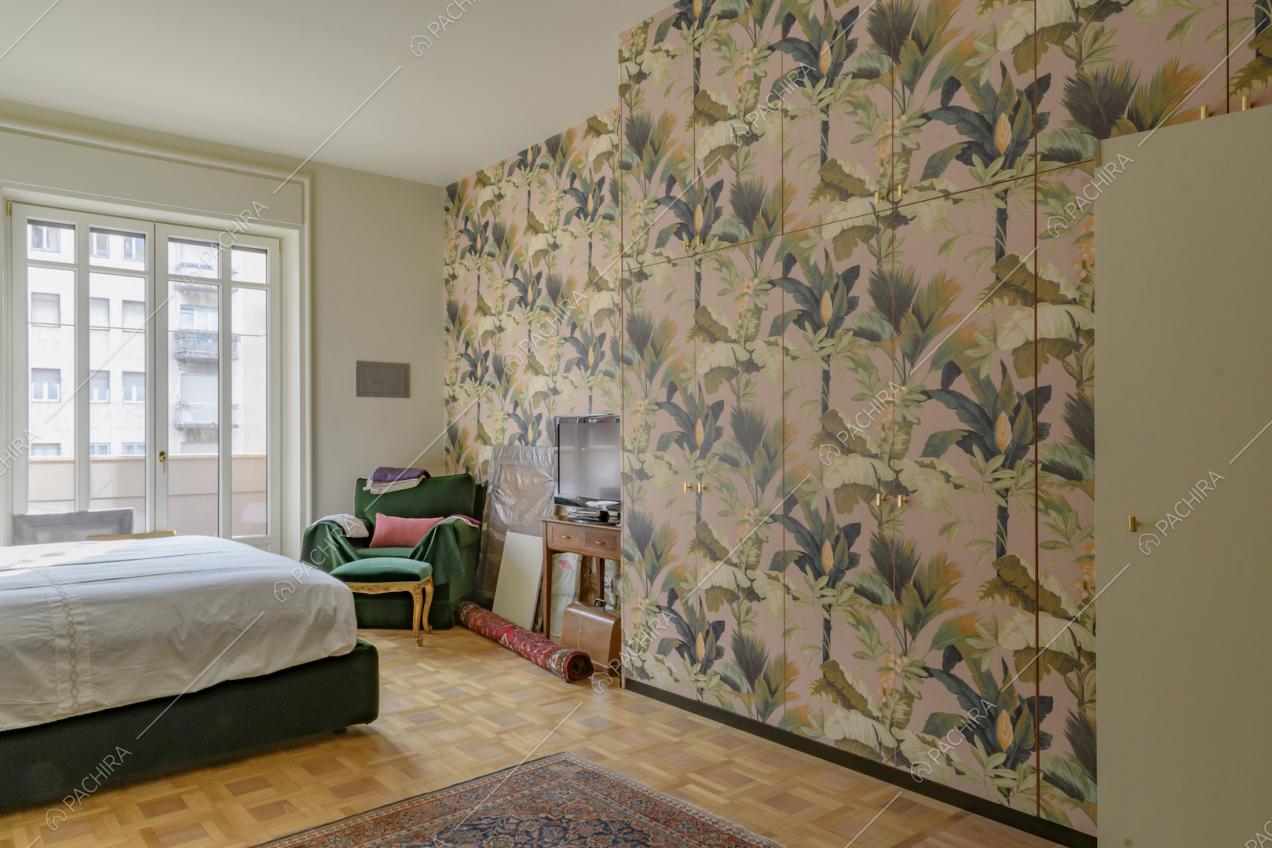 Camera da letto con pavimento in parquet, carta da parati sull'armadio a muro e porta-finestra