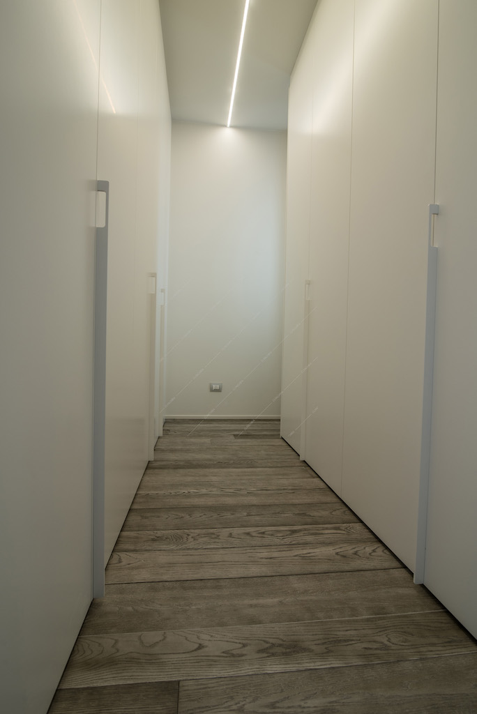 Corridoio con mobili bianchi e parquet a listoni