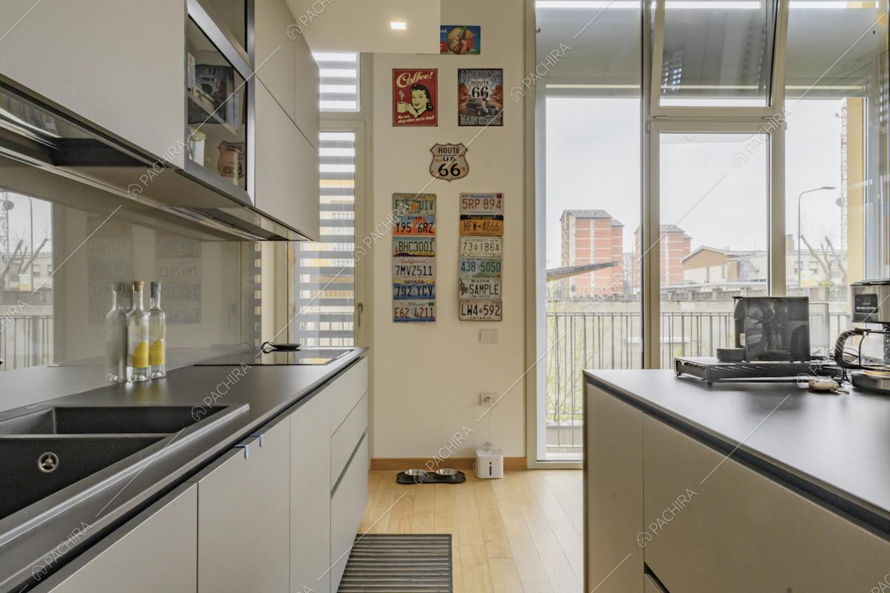 Cucina a isola con fornelli a induzione e porte-finestre per accedere al balcone