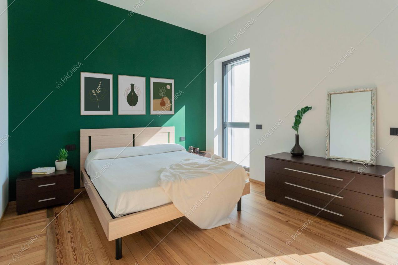 Camera da letto matrimoniale dal pavimento in parquet e dalle pareti verde e bianca