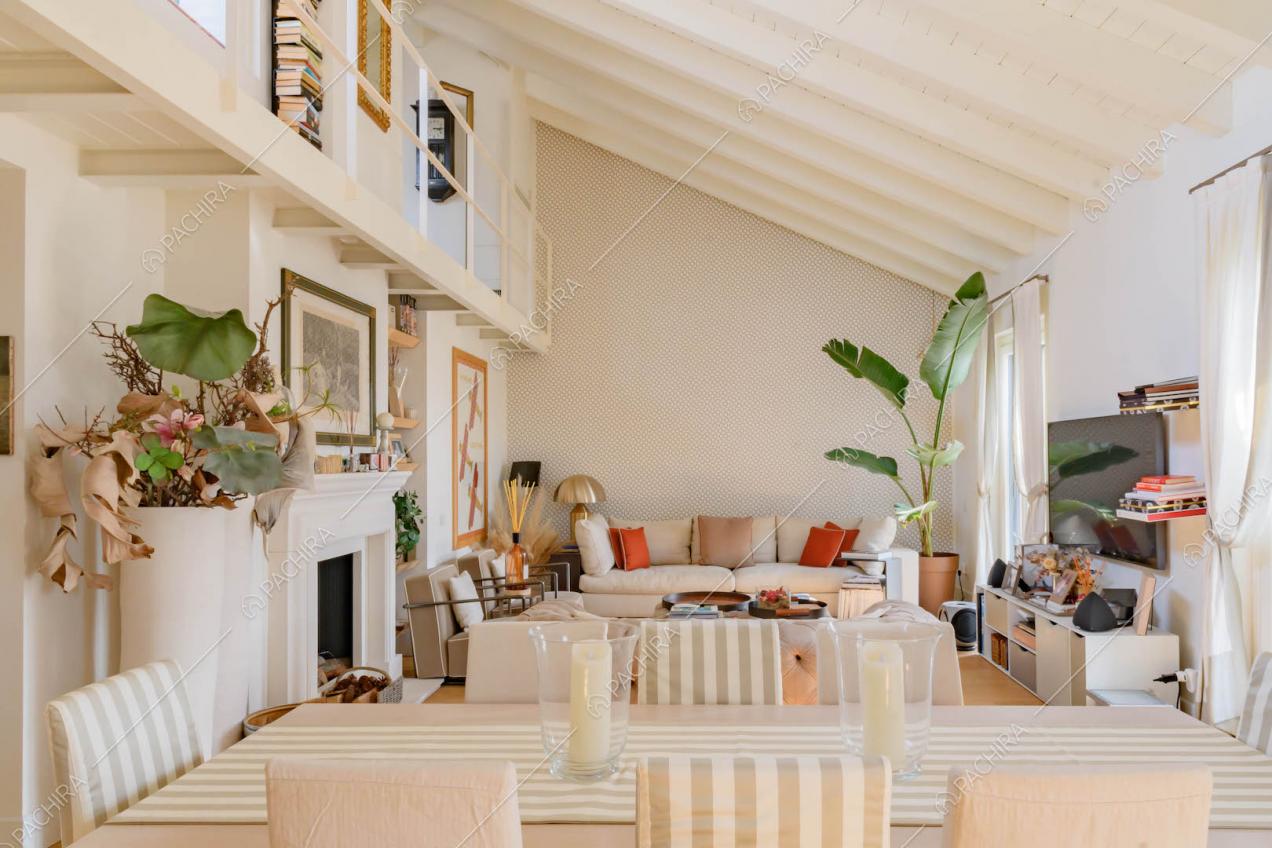 Tavolo da pranzo nella zona living con travi bianche a vista sul soffitto e camino