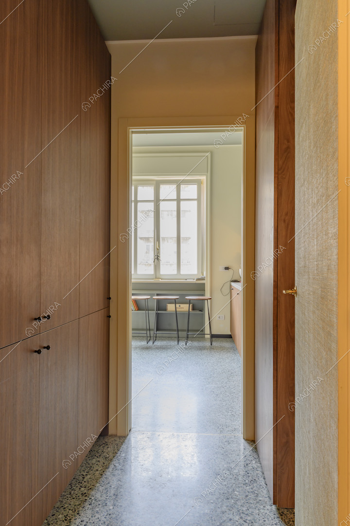 Corridoio con armadio a muro, pavimento in marmo e vista sugli sgabelli della cucina