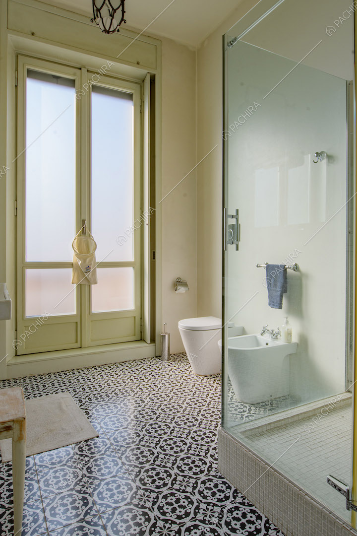 Ampio bagno con pavimento in piastrelle nere e bianche e box doccia con pareti in vetro