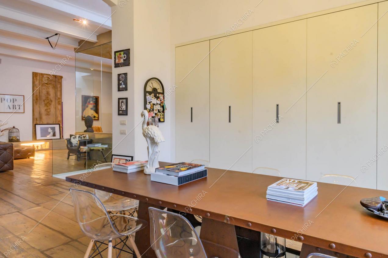 Tavolo da pranzo marrone nella cucina con armadi bianchi a muro e pavimento in parquet