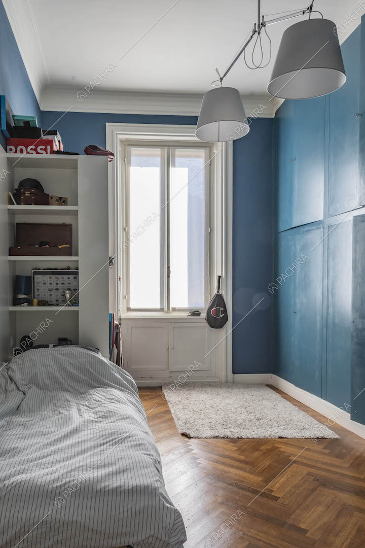 Camera da letto dalle pareti blu con armadio a parete e pavimento in parquet a spina di pesce
