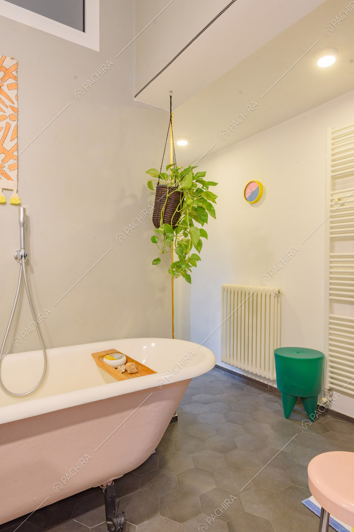 Vasca da bagno rosa, pavimento in cementine grigie e pareti bianche