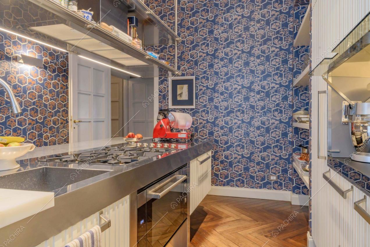 Cucina a isola con fornelli a gas, carta da parati e pavimento in parquet a spina di pesce