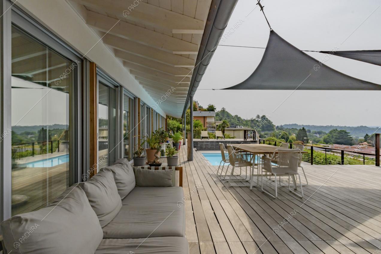 Diavano da esterni sotto al pergolato, tavolo da pranzo e piscina sulla terrazza con pavimento in parquet