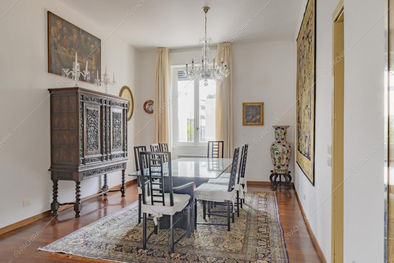Sala da pranzo in stile classico, con pavimento in parquet, pareti bianche e lampadario antico