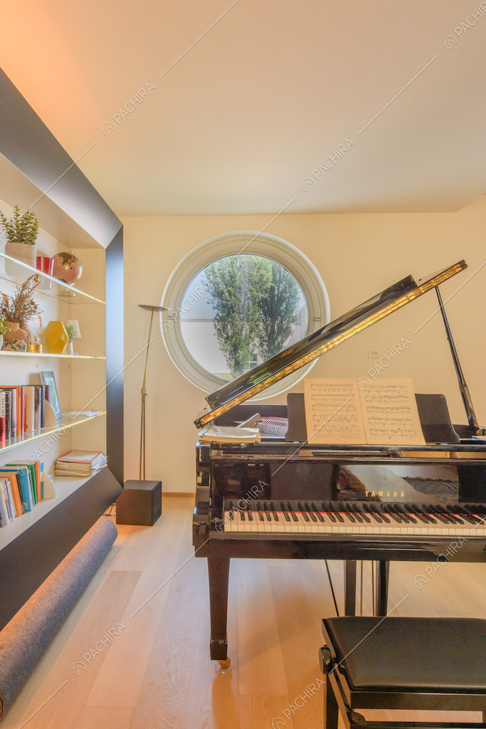 Pianoforte nero nel salotto con libreria e pavimento in parquet