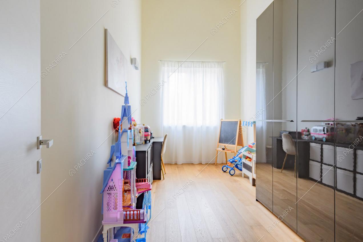 Camera con armadi neri, giochi, pavimento in parquet e pareti gialle