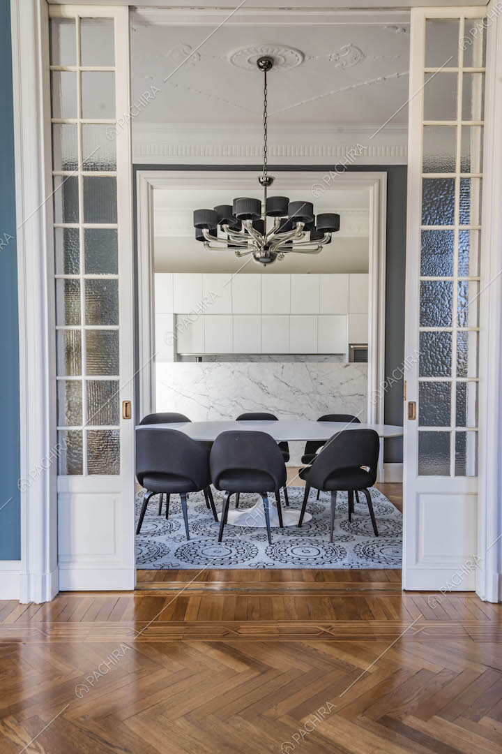 Vista sulla sala da pranzo con cucina a vista dal salotto con pavimento in parquet a spina di pesce