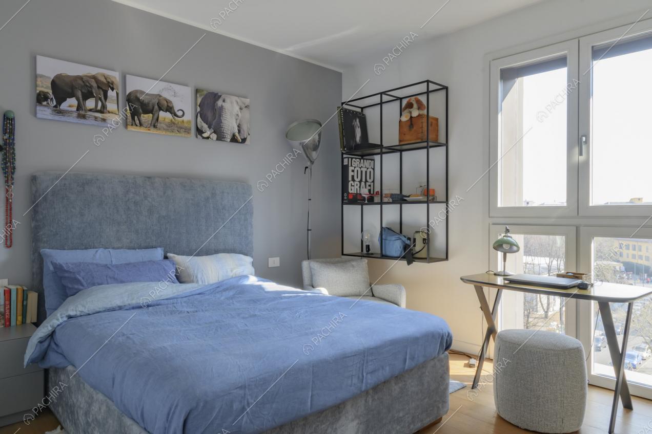 Luminosa camera da letto matrimoniale dalle pareti bianche e grigie