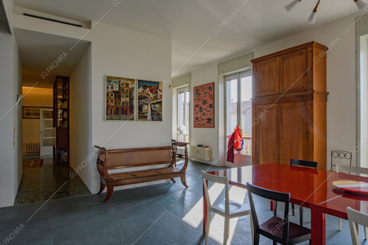 Tavolo rosso da pranzo nella sala con porte-finestre e vista sul corridoio con pavimento in marmo
