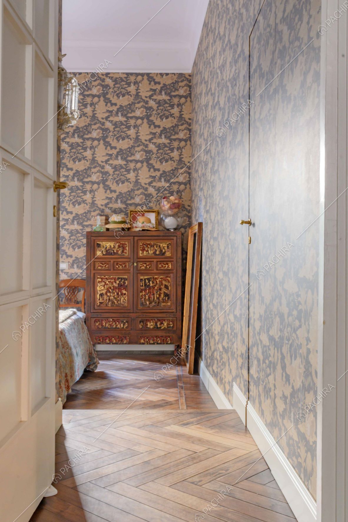 Dal corridoio vista sulla camera da letto matrimoniale con parquet a spina di pesce e carta da parati