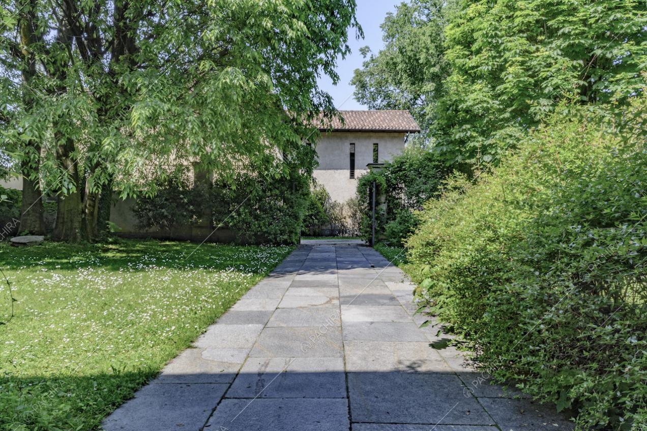 Vialetto in lastre di pietra della dimora storica immerso nel verde e scorcio sugli esterni