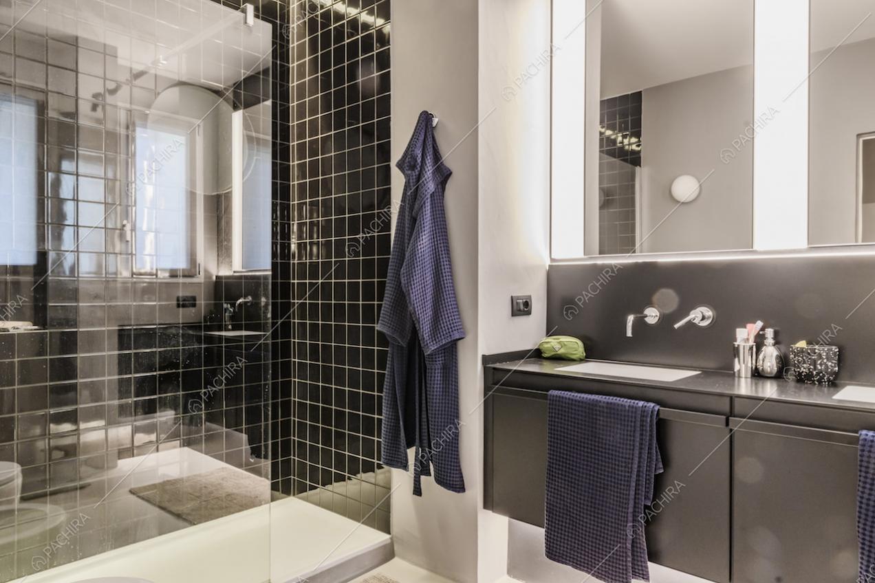 Bagno con piastrelle nere e cabina doccia