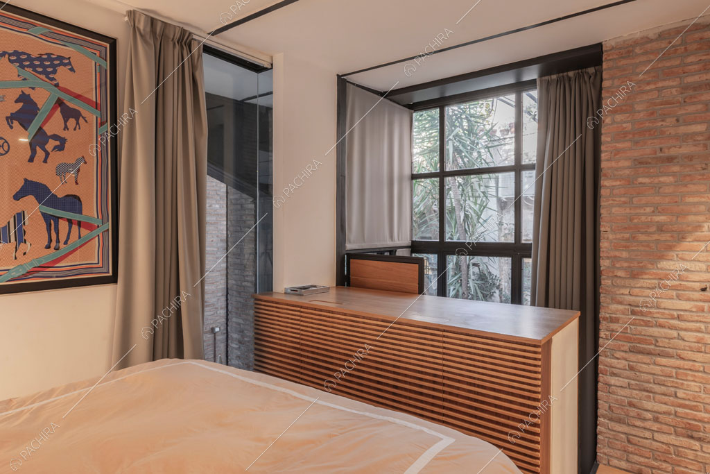 Parete con mattoni a vista nella camera da letto del loft Berillio, location in stile contemporaneo a Roma