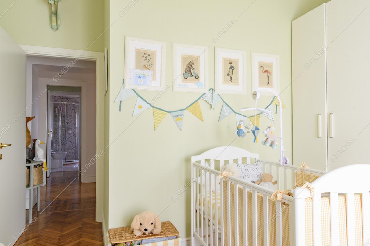 Camera dei bambini dalle pareti verdi, con culla e pavimento in parquet a spina di pesce