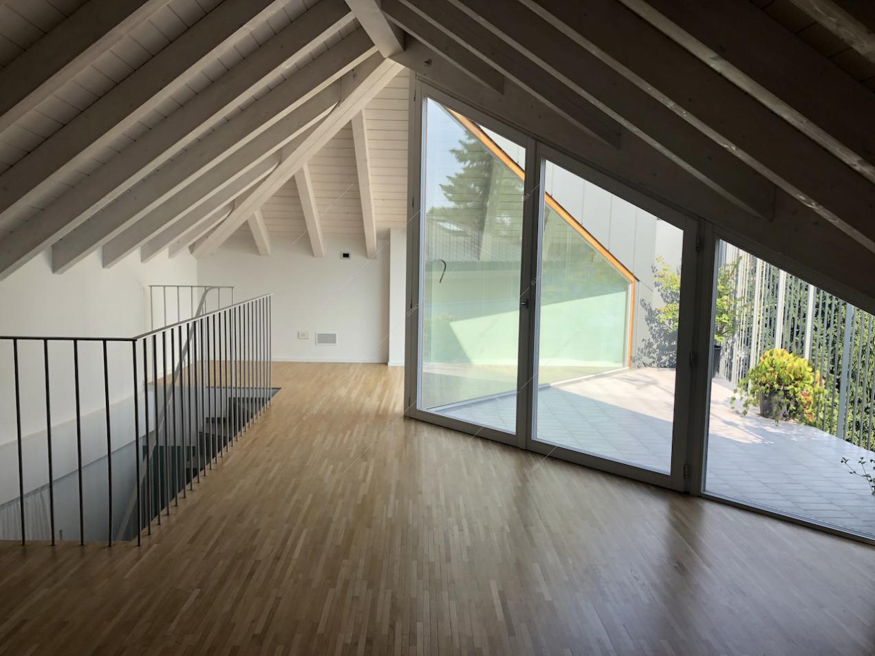 Sottotetto con travi a vista, vetrate e parquet