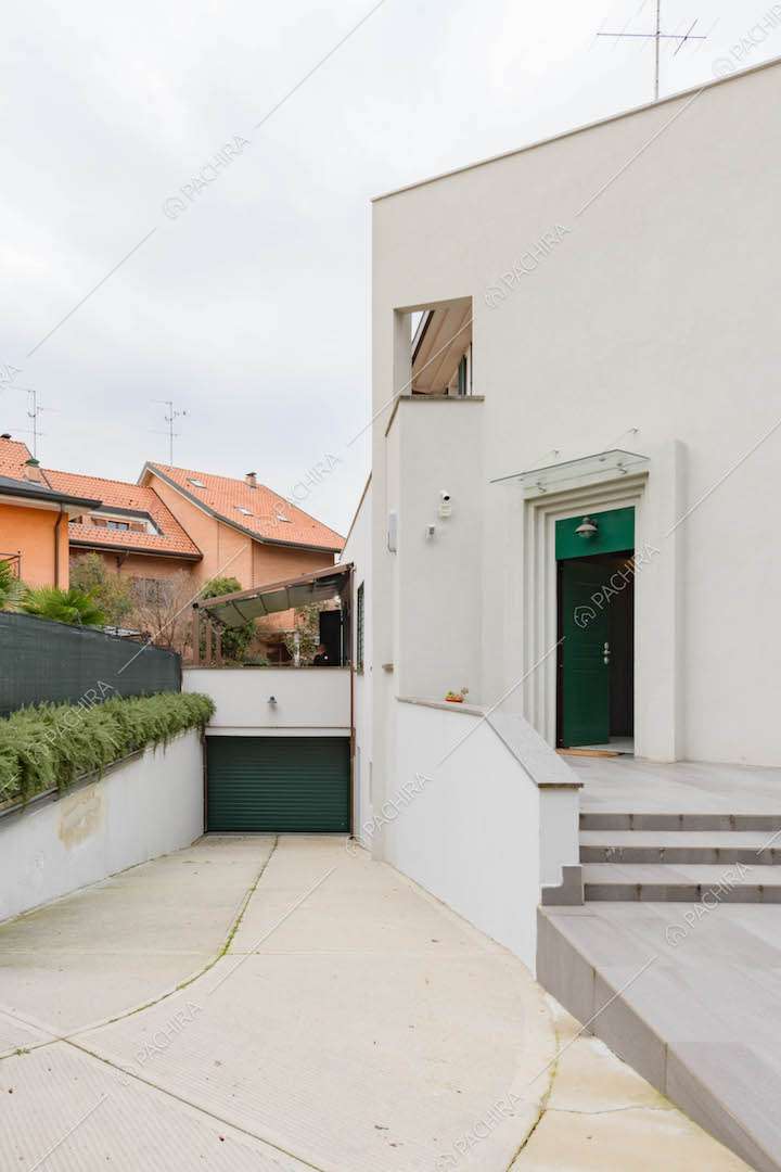 Esterni della location, vista sul garage e sulla porta d'ingresso verde con scalini di accesso