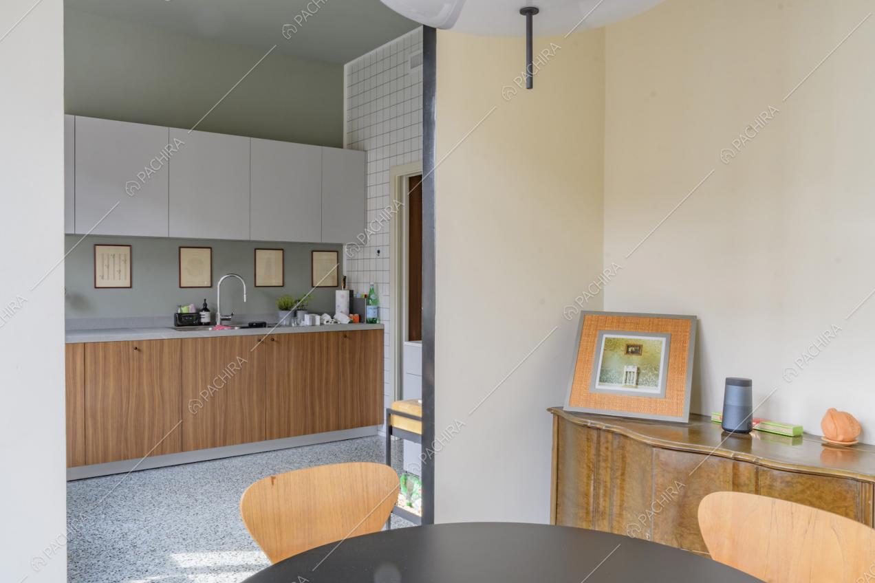 Dal tavolo da pranzo nero vista sulla cucina a muro con pavimento in marmo