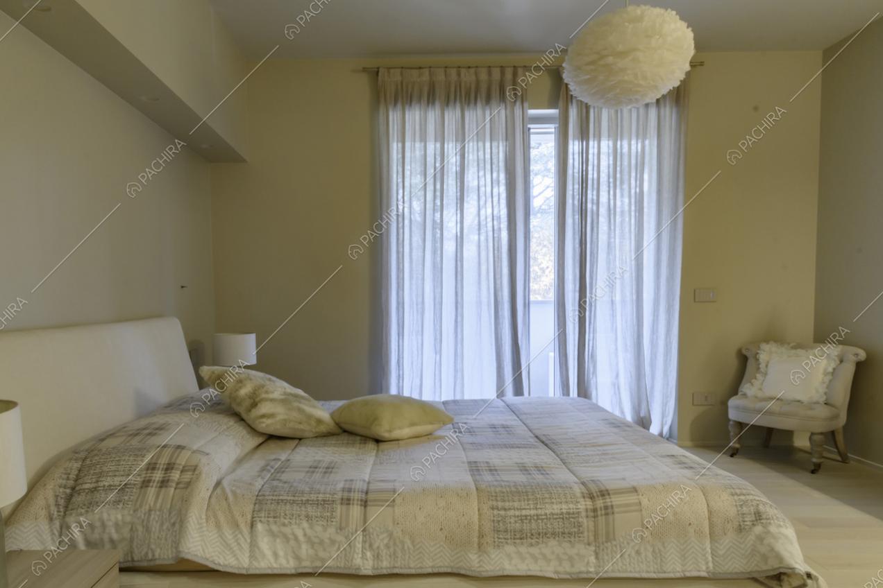 Camera da letto matrimoniale con poltrona e particolare lampadario