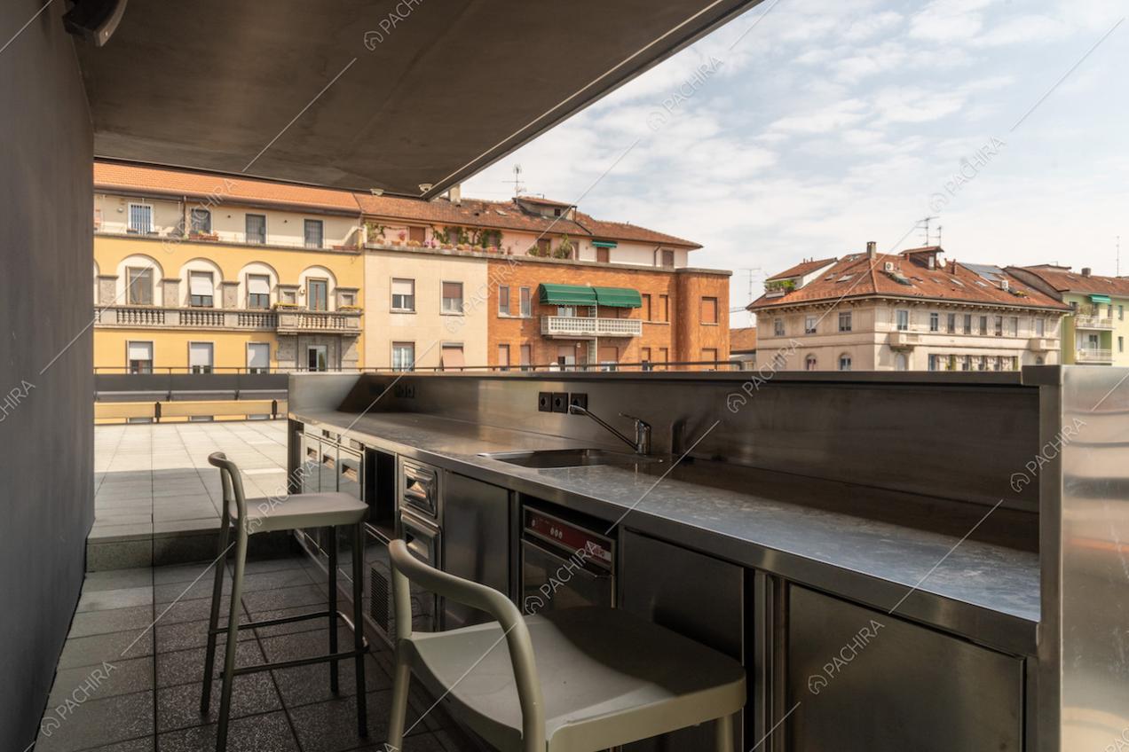 Bancone in metallo con sgabelli sulla terrazza con vista sullo skyline di Milano