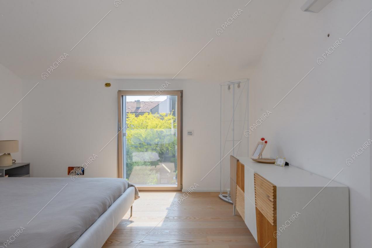 Luminosa camera da letto matrimoniale con vetrata e pavimento in parquet