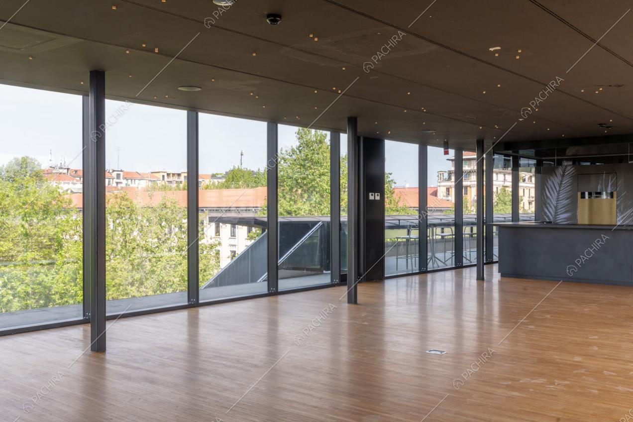 Dal salone con pavimento in parquet e bancone nero, vista sulla terrazza e le scale
