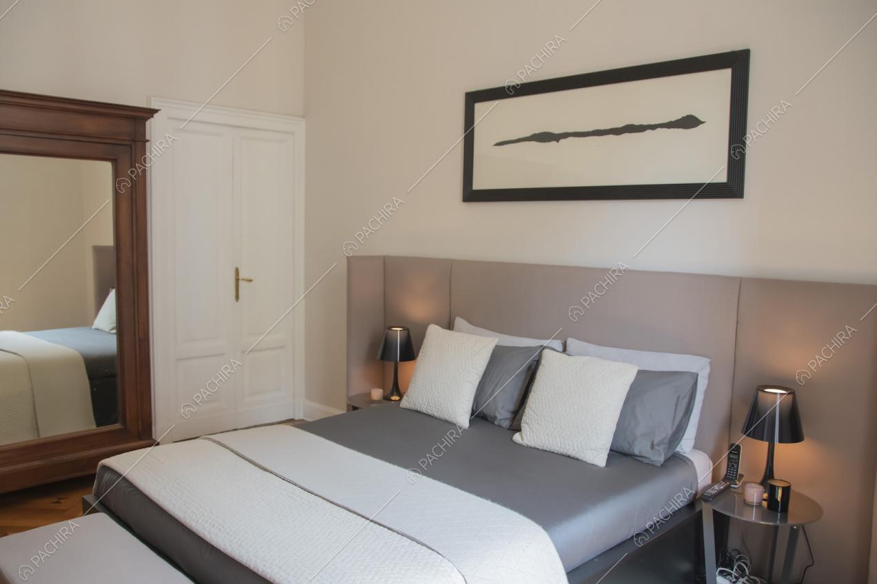 Letto matrimoniale nei toni del grigio e quadro astratto