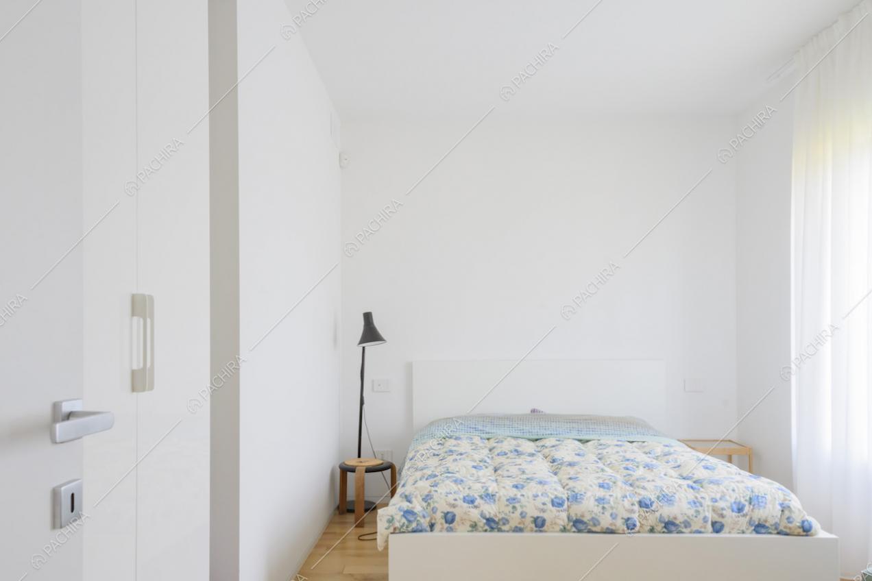 Camera con letto, pareti bianche e tende leggere